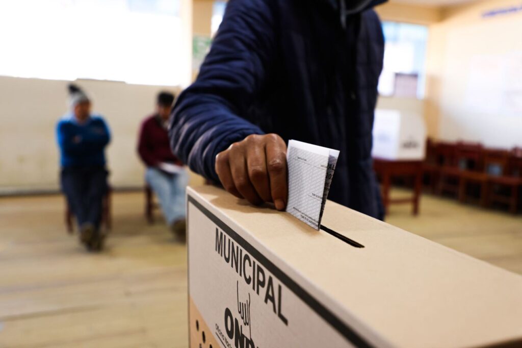 Ciudadano poniendo su voto en una urna de votación.